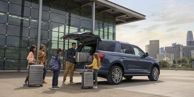 A family of 5 packing up their new spacious Ford Expedition with large suitcases, heading out to the airport
